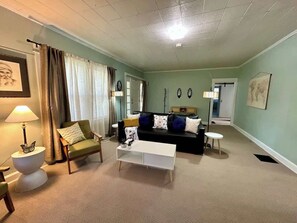Ein Wohnzimmer mit Sofa, Sessel, Couchtisch, Lampe und einem kleinen Tisch.