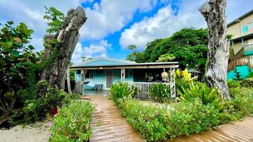 A beachfront property with a wooden deck, a covered porch, and lush greenery.