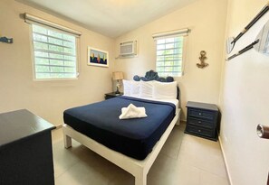 Ein Schlafzimmer mit einem Bett, Nachttischen, einem Schreibtisch und einem Fenster.