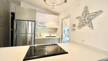 A modern kitchen with a central island, stainless steel appliances, and a decorative wall piece.