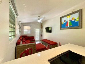 Ein gemütlicher Raum mit Küchenzeile, einem Essbereich mit Tisch und Stühlen, einer Sofagarnitur und einem an der Wand befestigten Fernseher.