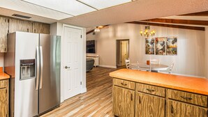 Una cocina con refrigerador, dispensador de agua, gabinetes de madera y un comedor con mesa y sillas.