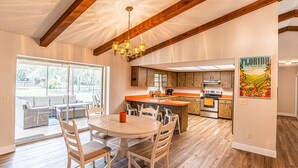 Cocina amplia con armarios de madera, una isla central y un comedor con mesa y sillas redondas.