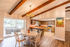 A spacious kitchen with wooden cabinets, a central island, and a dining area with a round table and chairs. - Sunkissed Sassa|8PPL|FencedYard|1Dogok|Grill|ScreenedPorch (Homosassa)