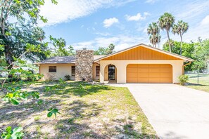 A single-story house with a stone pillar, a garage, and a well-maintained lawn. - Sunkissed Sassa|8PPL|FencedYard|1Dogok|Grill|ScreenedPorch (Homosassa)
