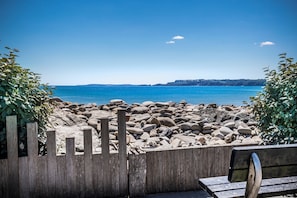 A wooden bench with a view of a rocky beach and calm sea. - Smugglers Cove - Short Walk to Beach (Amroth)