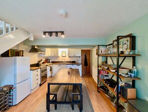 A kitchen with a wooden table, white cabinets, a built-in oven, a dishwasher, and a wine rack. - Cosy 2bed house in Reading (Reading)