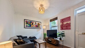 Ein Wohnzimmer mit einer Couch, Fernseher, Lampe und Kunstwerken.