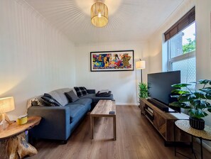 A modern living room with a sofa, coffee table, TV stand, and artwork on the wall. - Cosy 2bed house in Reading (Reading)