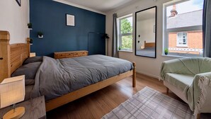 Ein Schlafzimmer mit Bett, Nachttisch, Lampe und Blick ins Freie.