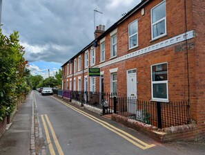 A row of red brick houses with a 'Prospect' sign, a clear road, and a sidewalk. - Cosy 2bed house in Reading (Reading)