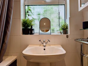 A bathroom with a white sink, a window with a view of greenery, and a mirror above the sink. - Cosy 2bed house in Reading (Reading)