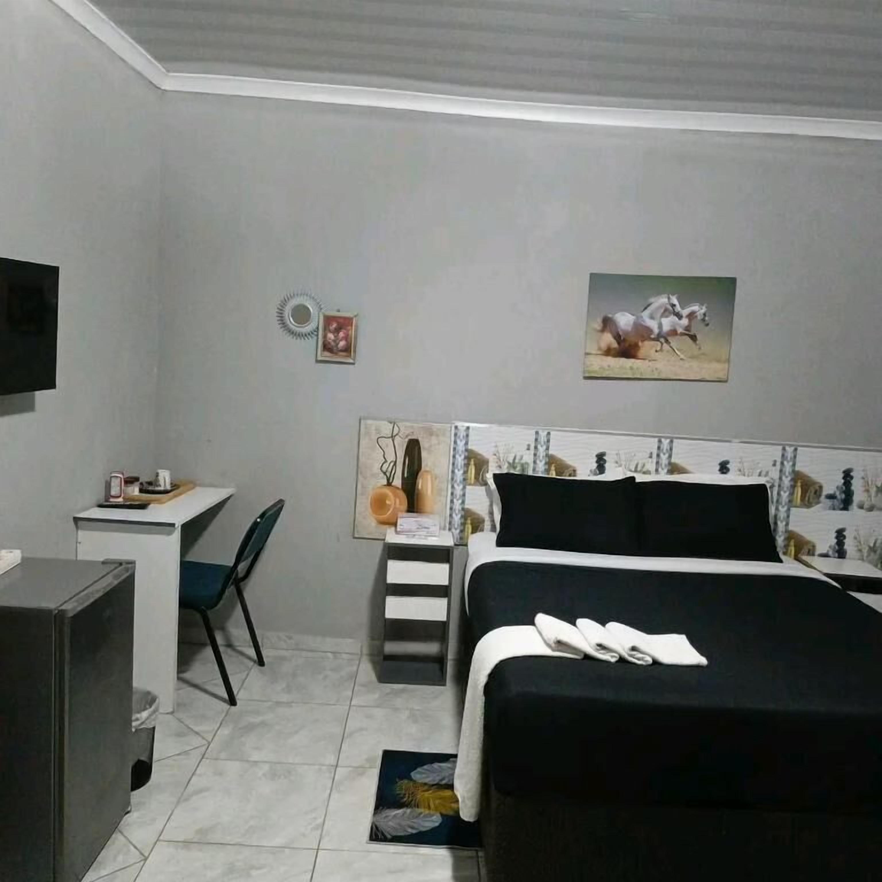 Une chambre à coucher avec un lit, un bureau, une chaise et un téléviseur.