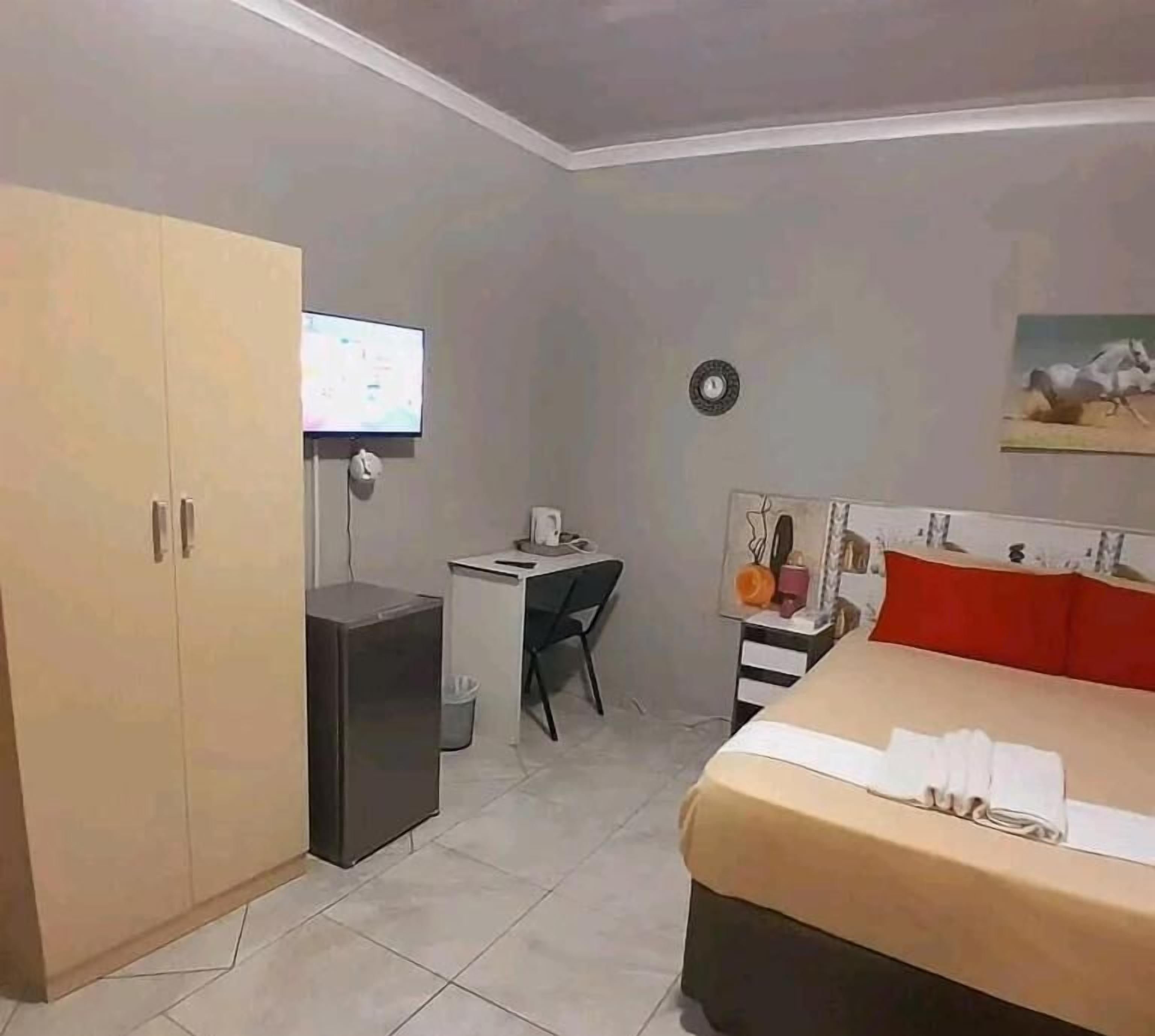 Um quarto com uma cama, uma escrivaninha, uma televisão e um guarda-roupa.