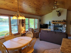 A cozy living room with a fireplace, a television, and a dining area with a table and chairs.
