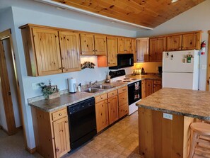 A kitchen with wooden cabinets, a dishwasher, a stove, a microwave, and a refrigerator.