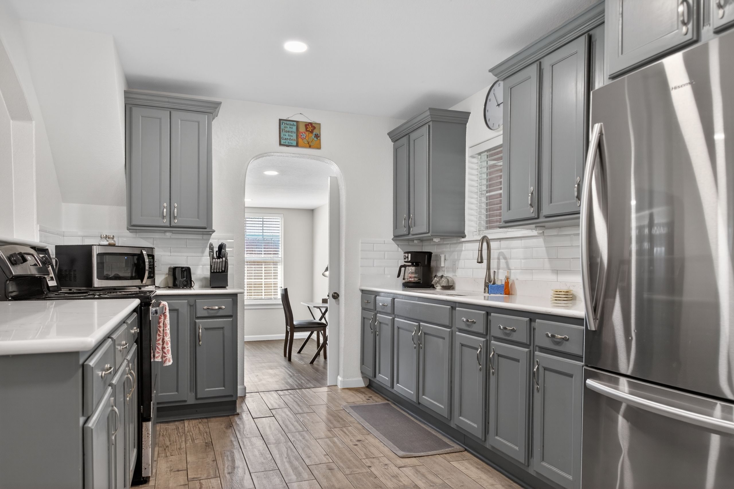 A kitchen featuring gray cabinetry, stainless steel appliances, and an arched entry.
