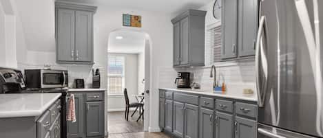 A kitchen featuring gray cabinetry, stainless steel appliances, and an arched entry.