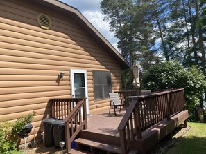 A wooden house with a deck, a door, and a window.