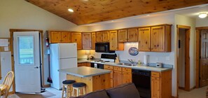 A kitchen with wooden cabinets, a refrigerator, a microwave, and a sink.