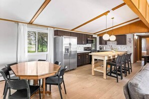 Eine kompakte Küche mit Kochinsel, Holzschränken und einem Edelstahlkühlschrank.