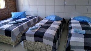 A room with three beds, each with a checkered bedspread and blue pillows.
