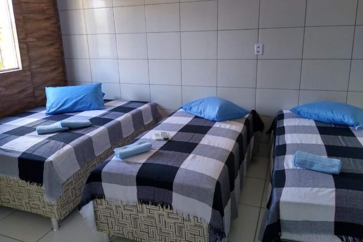 A room with three beds, each with a checkered bedspread and blue pillows.