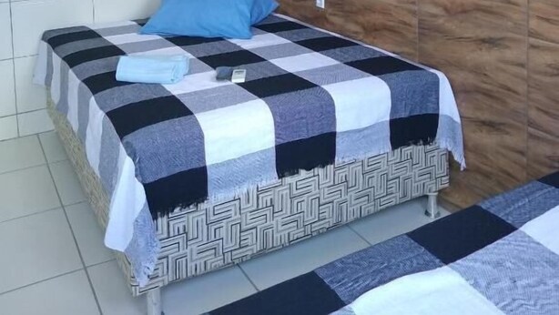 A room with a bed, a wall-mounted air conditioner, and a patterned wall.
