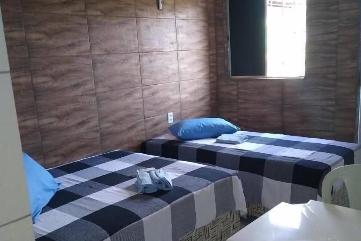 A room with two beds, a white table, and a window.
