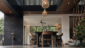 A modern interior with a dining area, staircase, and hanging light fixtures. - Oran Villa Bali (Tampaksiring)