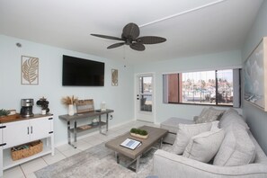 A living room with a sofa, coffee table, TV, and a ceiling fan.