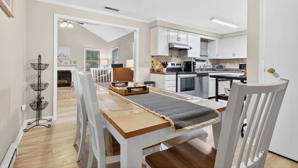 Una cocina moderna con armarios blancos, una mesa de comedor con sillas y una chimenea a la vista.