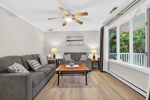 Ein Wohnzimmer mit Deckenventilator, einer Couch, einem Couchtisch und zwei Lampen.