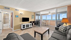 Ein Wohnzimmer mit Fernseher, einer weißen Unterhaltungseinheit, einem Couchtisch und einem Sofa.
