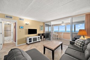 Ein Wohnzimmer mit Fernseher, einer weißen Unterhaltungseinheit, einem Couchtisch und einem Sofa.