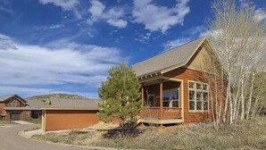 A wooden cabin with a porch, a garage, and a small tree in front. - Ski In Ski Out Marvel with golf, biking, pool and fishing (Granby)