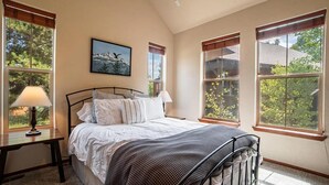 A bedroom with a bed, two bedside tables, a window with a view, and a painting on the wall. - Ski In Ski Out Marvel with golf, biking, pool and fishing (Granby)