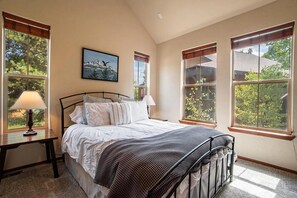 Ein Schlafzimmer mit einem Bett, zwei Nachttischen, einem Fenster mit Aussicht und einem Bild an der Wand.