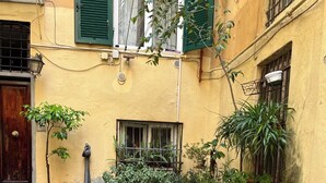 Un patio con suelo de piedra, plantas en macetas, un banco de madera y una puerta.