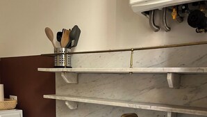 Una cocina con un lavabo blanco, una estufa empotrada y una barra para colgar ollas.