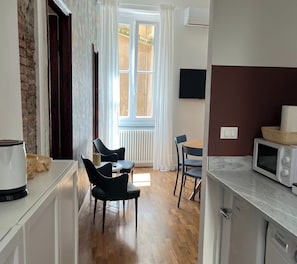 A modern kitchen with a microwave, a Bosch dishwasher, and a dining area with chairs and a table. - Elegantly renovated apartment next to Aquarium & Waterfront (Genova)