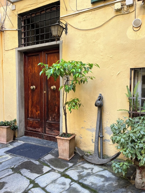 A yellow building with a wooden door, a potted plant, and a metal anchor decoration. - Elegantly renovated apartment next to Aquarium & Waterfront (Genova)