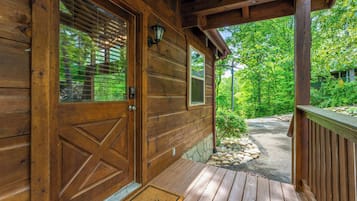 A wooden cabin with a porch, a door with a window, and a welcome mat.