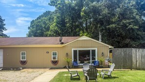 A single-story building with a garage, a covered patio area with chairs, and a wooden fence. - Beautiful 2-bedroom cottage with AC in charming Lanexa (Lanexa)