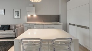 A modern kitchen with a white island, clear chairs, and a pendant light. - Valor by Grand Apartments (Sopot)