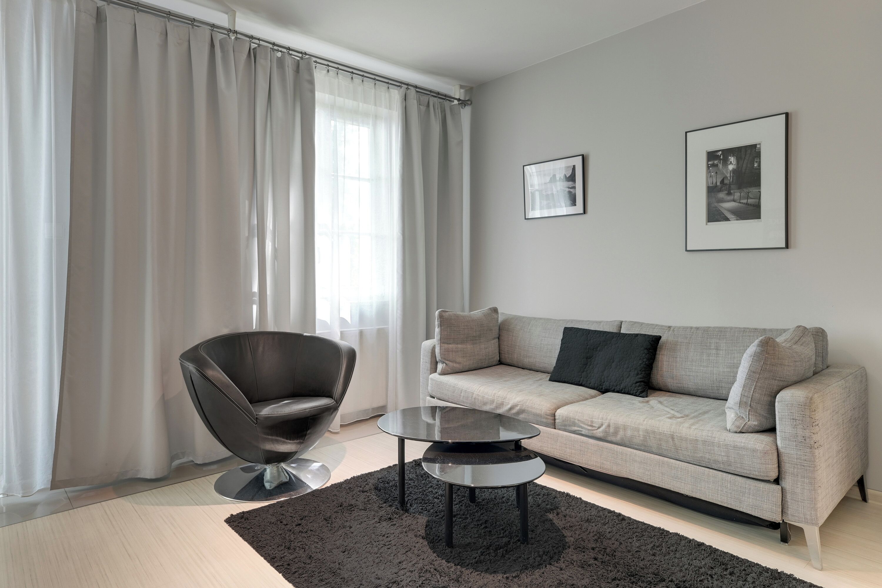 A modern living room with a sofa, a chair, a coffee table, and two framed pictures on the wall.