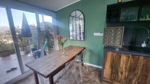 Una cocina con una mesa y sillas de madera, una pared verde y una ventana con vista a un jardín.