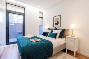 Un dormitorio con cama, mesita de noche, lámpara, un cuadro enmarcado y una puerta corredera.