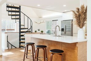 Una cucina moderna con isola centrale, scala a chiocciola e pavimento in legno.