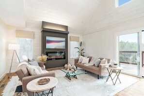 Ein modernes Wohnzimmer mit Kamin, einer Couch, einem Couchtisch und einem Fernseher.